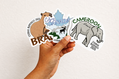Hand holding a collection of international convention stickers with various designs on a white background