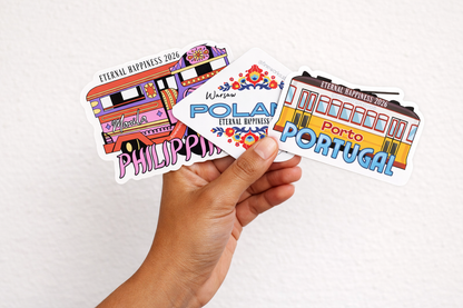 Hand holding a collection of international convention stickers with various designs on a white background