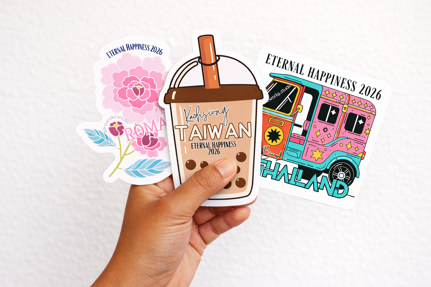 Hand holding a collection of international convention stickers with various designs on a white background